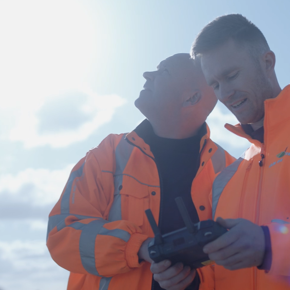 Twee werknemers op een zandput besturen een drone.